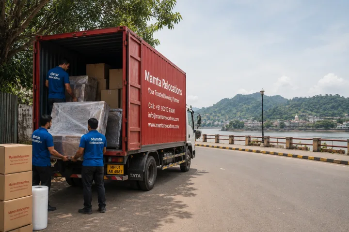 Mamta Relocations crew loading stretch-wrapped furniture and labelled cartons into their truck on a Guwahati road near the Brahmaputra