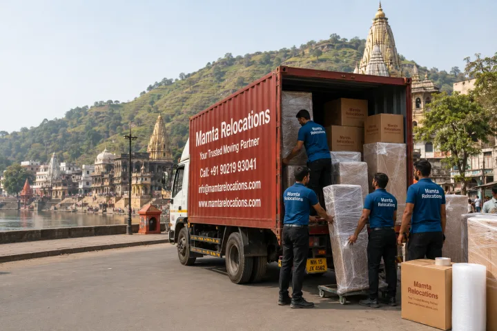 Mamta Relocations crew loading stretch-wrapped furniture and labelled cartons into their truck on a Nashik road near the Godavari ghats with