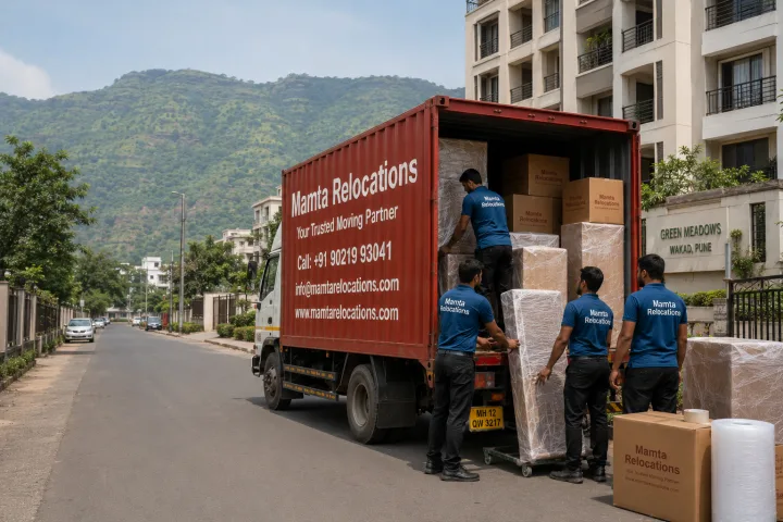 Mamta Relocations crew loading stretch-wrapped furniture and labelled cartons into their truck outside a Pune residential society with the green