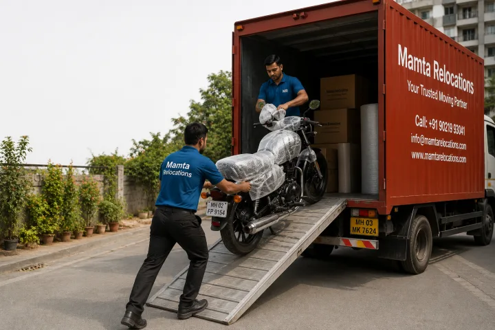 Motorcycle being wheeled up a ramp into the truck while a crew member wraps the handlebar and fuel tank with bubble wrap — Mamta Relocations